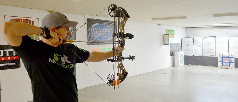 Keith Bryant/The Weekly Vista John Curtis with Hook Line &amp; Sinker in Bentonville lines up a shot in the fishing and archery shop's basement archery range.