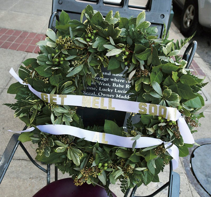 The Sentinel-Record/Grace Brown NOT FORGOTTEN: A gifted wreath from Johnson Floral Co. sits in Al Capone's usual seat outside of the Ohio Club in downtown Hot Springs after an alleged act of criminal mischief in March 2018.