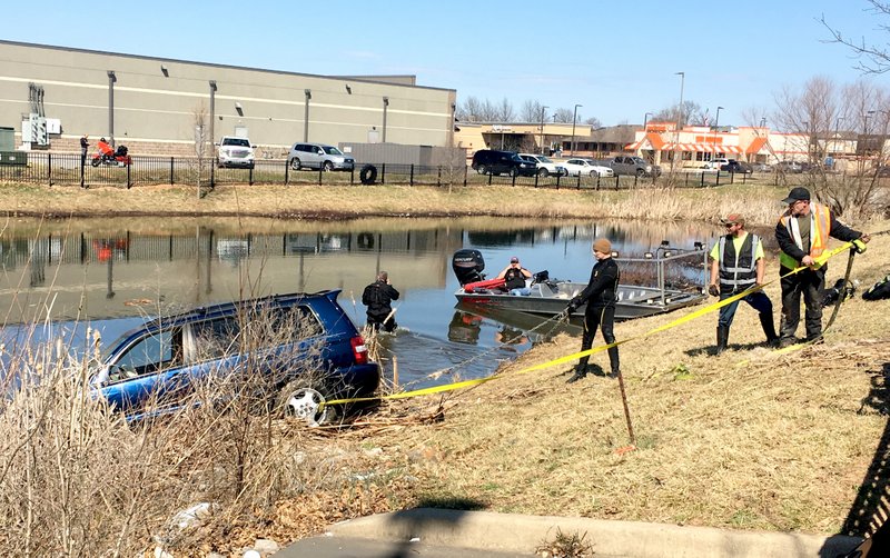 NWA Democrat-Gazette/TRACY NEAL Crews pull a car out of a retention pond Monday next to the Walmart Supercenter at Pleasant Grove Road in Rogers.