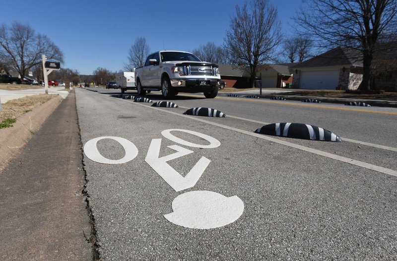 NWA Democrat-Gazette/FLIP PUTTHOFF Vehicles move Saturday along Dick Smith Street in Springdale between barriers installed to create bike lanes on each side of the street.
