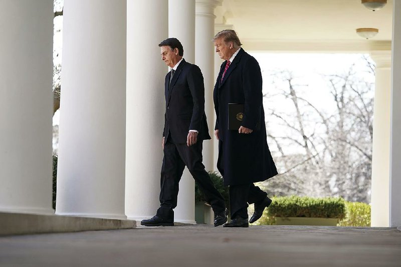 Brazilian President Jair Bolsonaro and President Donald Trump walk to a news conference Tuesday at the White House. Trump said he would like to make Brazil part of NATO, although Brazil doesn’t qualify for membership. 