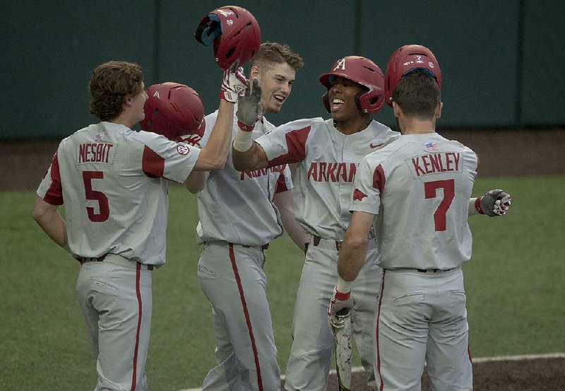 Arkansas outfielder Christian Franklin (second from right) celebrates his second-inning grand slam with Jacob Nesbit (5), Jack Kenley (7) and Matt Goodheart against Texas on Tuesday in Austin, Texas. The Razorbacks won 11-4. 