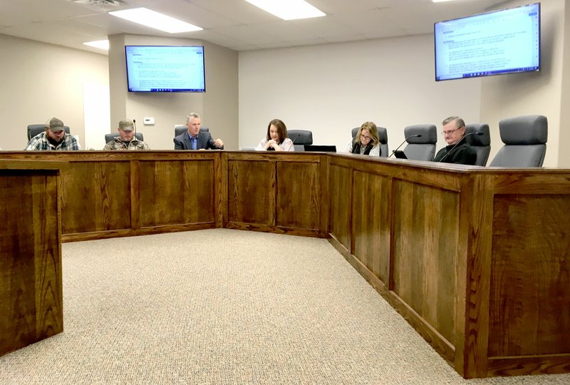 Westside Eagle Observer/RANDY MOLL Members of the Highfill City Council review an agenda item at the March 12 meeting in Highfill's city hall. The council uses iPads rather than paper copies, and the documents are displayed on large-screen TVs for those attending the meetings.