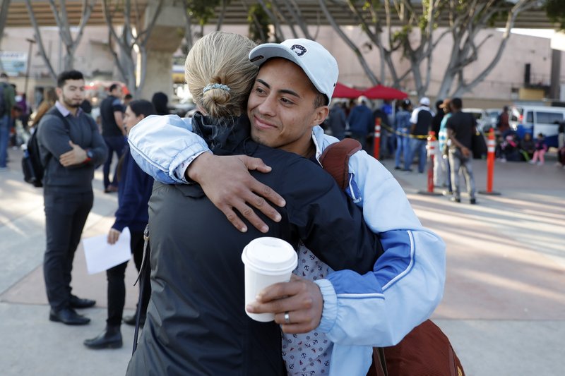 A man who only gave his first name as Ariel, of Honduras, hugs an attorney before crossing into the United States to begin his asylum case after being returned to Mexico, Tuesday, March 19, 2019, in Tijuana, Mexico. A group of about five men were on their way to report for their first hearing under a new policy to make asylum seekers wait in Mexico while their case winds through U.S. immigration court. (AP Photo/Gregory Bull)