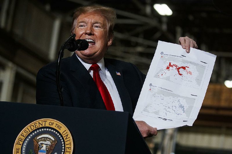 President Donald Trump, speaking Wednesday in Lima, Ohio, holds up a map showing the decrease in land controlled by ISIS forces in Iraq and Syria since he took office. 