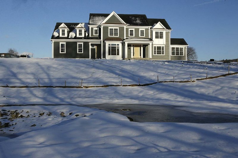 Long-term mortgage rates have continued their fall this week, creating incentive for sales of homes like this one surrounded by snow last month in Natick, Mass. 