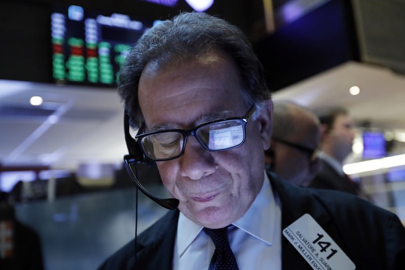 In this March 12, 2019, file photo a handheld device of trader Sal Suarino is reflected in his glasses as he works on the floor of the New York Stock Exchange.  (AP Photo/Richard Drew, File)