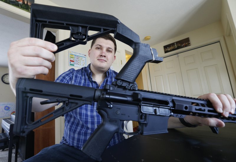 In this March 15, 2019 photo, Ryan Liskey displays a bump stock on top of his AR-15 at his home in Harrisonburg, Va. The ban on bump stocks is just a few days away and owners of the devices like Liskey are trying to figure out what to do. (AP Photo/Steve Helber)