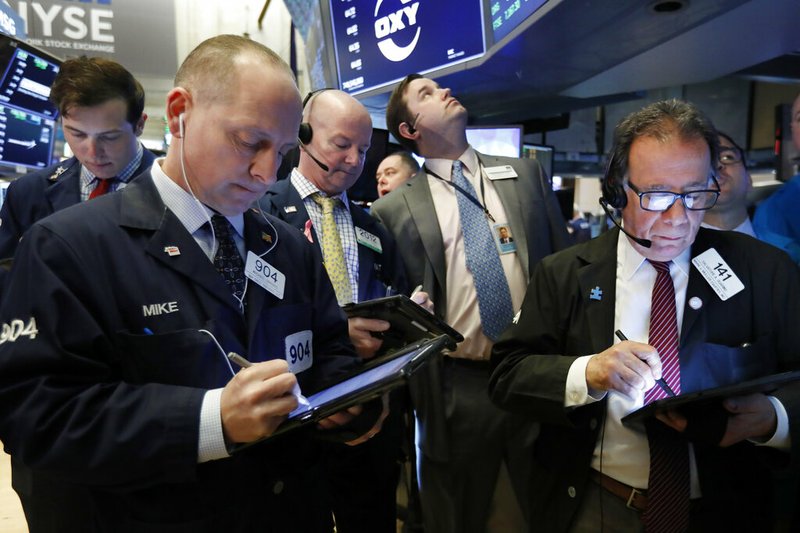 In this March 13, 2019, file photo traders gather at the post that handles Oaktree Capital Group on the floor of the New York Stock Exchange. The U.S. stock market opens at 9:30 a.m. EDT on Friday, March 22. (AP Photo/Richard Drew, File)