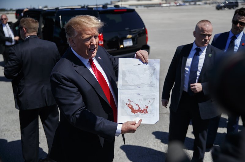 President Donald Trump holds a a copy of two maps of Syria as he arrives on Air Force One, Friday, March 22, 2019, at Palm Beach International Airport, in West Palm Beach, Fla. (AP Photo/Carolyn Kaster)