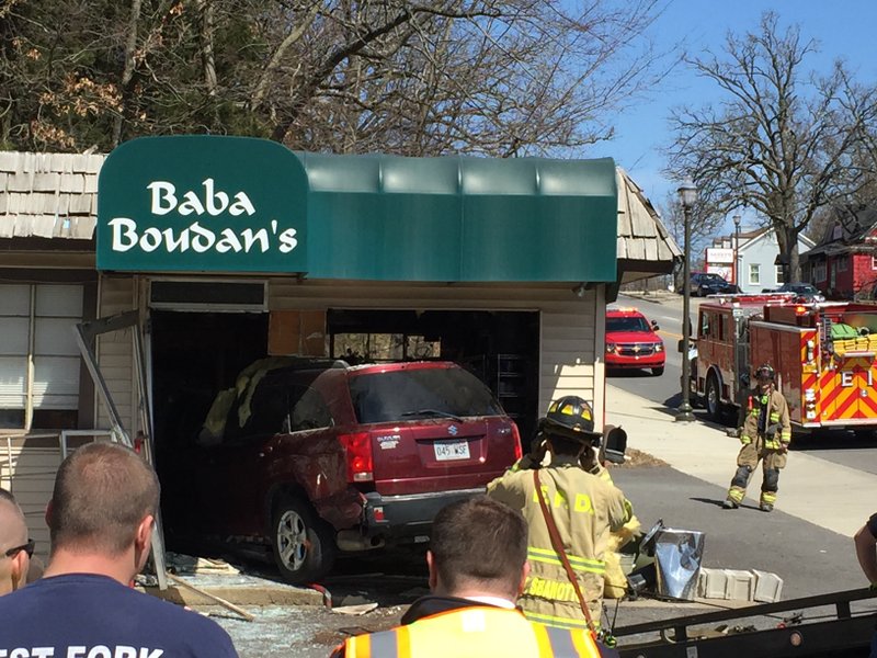 NWA Democrat-Gazette/Bill Bowden Crews pull a vehicle from Baba Boudan’s, 701 N. College Ave., in Fayetteville. Police said a collision on the highway caused the car to careen into the building.