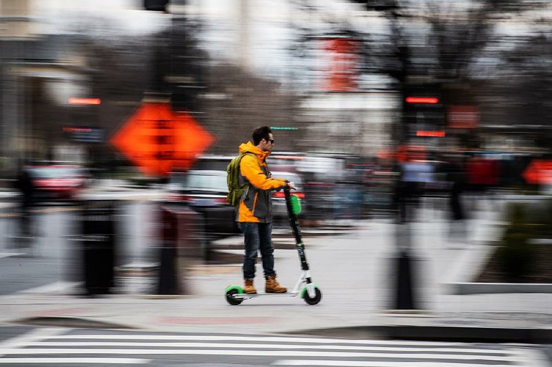 A helmetless electric scooter rider zips along a street in Washington, D.C. The devices are in dozens of cities across the United States, including Little Rock, and have spawned a new category of emergency room injuries. 