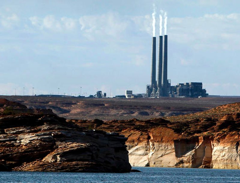 FILE - In this Sept. 4, 2011, file photo, smoke rises from the stacks of the main plant facility at the Navajo Generating Station, as seen from Lake Powell in Page, Ariz. The Navajo Nation company has ended its pursuit of a coal-fired power plant on the reservation and the mine that feeds it. The decision Friday, March 22, 2019 means the Navajo Generating Station and the Kayenta Mine will close this year, ending decades of operation in northeastern Arizona. The bid by the Navajo Transitional Energy Company had been considered a long-shot. (AP Photo/Ross D. Franklin, File)