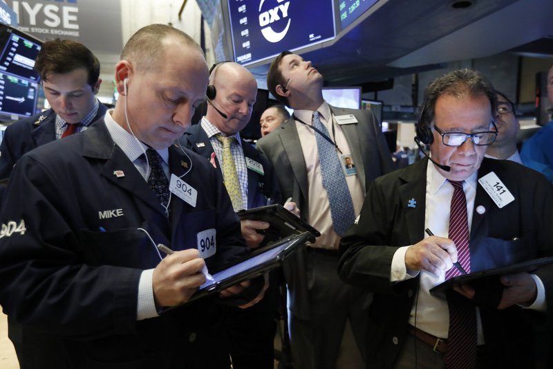 FILE- In this March 13, 2019, file photo traders gather at the post that handles Oaktree Capital Group on the floor of the New York Stock Exchange. The U.S. stock market opens at 9:30 a.m. EDT on Friday, March 22. (AP Photo/Richard Drew, File)