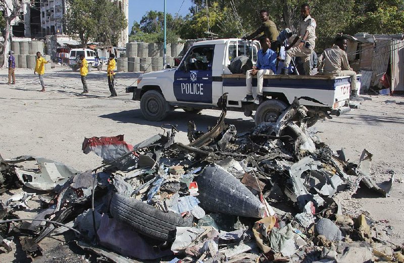 A police vehicle passes the wreckage from Saturday’s attack on a government building in Mogadishu, Somalia. 