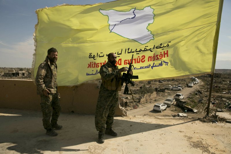 U.S.-backed Syrian Democratic Forces (SDF) fighters pose for a photo on a rooftop overlooking Baghouz, Syria, after the SDF declared the area free of Islamic State militants after months of fighting on Saturday, March 23, 2019. The elimination of the last Islamic State stronghold in Baghouz brings to a close a grueling final battle that stretched across several weeks and saw thousands of people flee the territory and surrender in desperation, and hundreds killed. (AP Photo/Maya Alleruzzo)