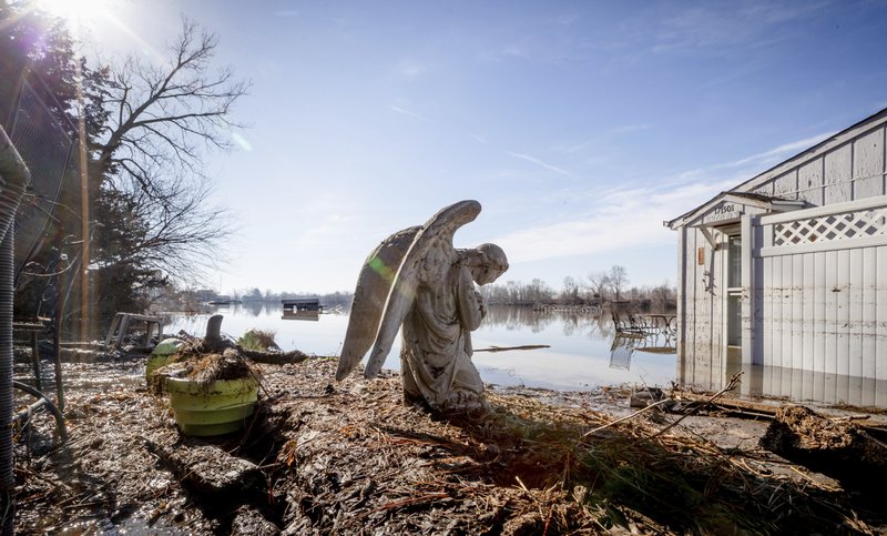 An angel statuary graces a yard near Hansen Lake Friday, March 22, 2019, in Bellevue, Neb. Residents were allowed into the area for the first time since floodwaters overtook several homes. Flooding in Nebraska has caused an estimated $1.4 billion in damage. The state received Trump's federal disaster assistance approval on Thursday. (Kent Sievers/Omaha World-Herald via AP)