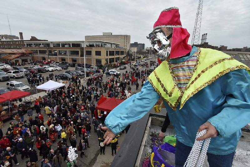Scott Lowell, of Grosse Pointe Park, throws colored-necklaces to revelers down below during the Marche du Nain Rouge, in Detroit, on Sunday. The Nain Rouge is a legendary hobgoblin creature whose appearance is believed to bring misfortune to Detroit. 