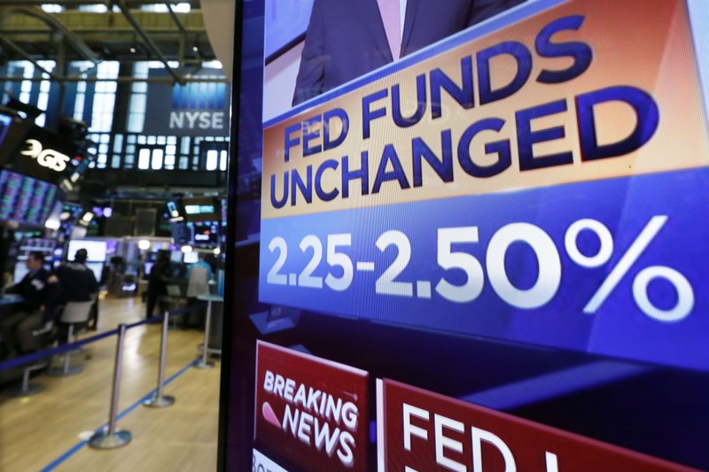 A screen on the floor of the New York Stock Exchange shows the rate decision of the Federal Reserve, Wednesday, March 20, 2019. The Federal Reserve is leaving its key interest rate unchanged and projecting no rate hikes in 2019, dramatically underscoring its plan to be &quot;patient&quot; about any further increases. (AP Photo/Richard Drew)