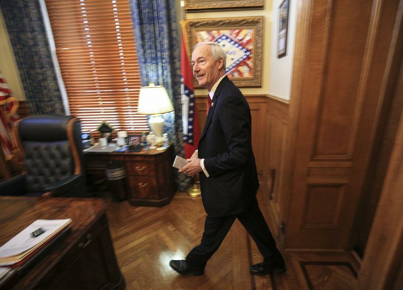 Gov. Asa Hutchinson arrives Monday in his office at the state Capitol. At a news conference the governor discussed a variety of subjects, including a proposal to create a pilot, private school voucher program in Pulaski County. More photos are available at www.arkansasonline.com/326genassembly/.