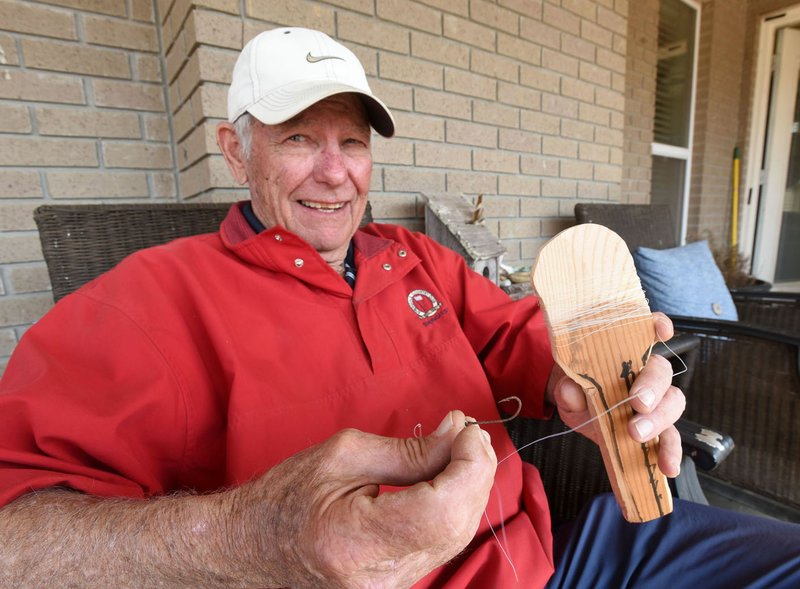 NWA Democrat-Gazette/FLIP PUTTHOFF Pat Hanby of Springdale shows March 19 2019 his wooden paddle-shaped fishing device. A toss of some line and a hook with bait attached allows it to cast similar to line coming off a spin-cast reel. Hanby fished with it on the Kings River when he was a boy.