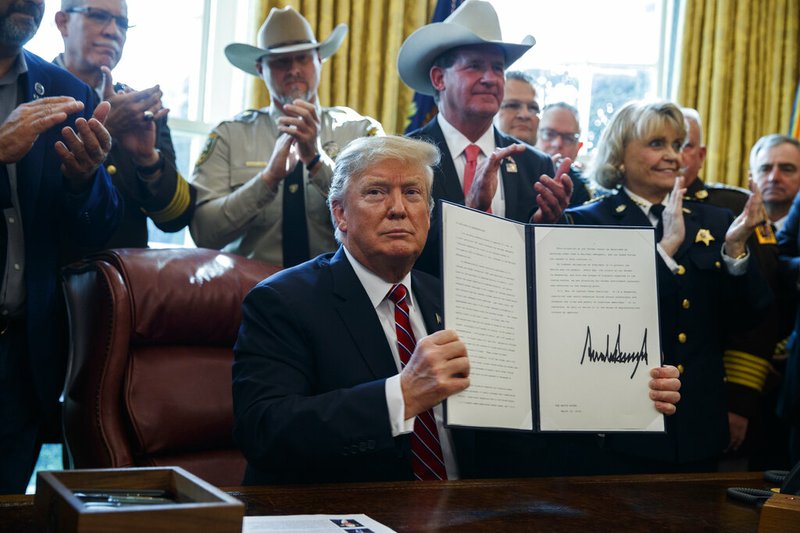 President Donald Trump signs the first veto of his presidency in the Oval Office of the White House, Friday, March 15, 2019, in Washington. Trump issued the first veto, overruling Congress to protect his emergency declaration for border wall funding. (AP Photo/Evan Vucci)