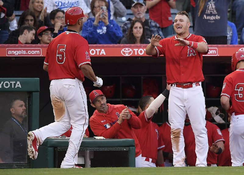 Los Angeles Angels' Albert Pujols, left, is congratulated by Mike Trout, right, as manager Brad Ausmus watches during the fourth inning of the team's preseason baseball game against the Los Angeles Dodgers on Sunday, March 24, 2019, in Anaheim, Calif. 