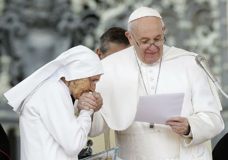 Sister Maria Concetta Esu, 85, kisses the hand of Pope Francis as he presents her with a Pro Ecclesia et Pontifice award during his weekly general audience, in St. Peter’s Square, at the Vatican on Wednesday. 