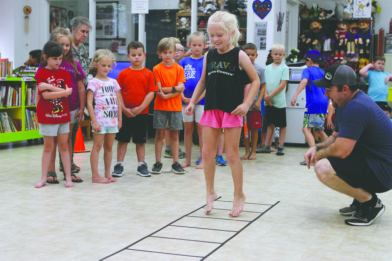 Boot camp: Austin Harrell, right, watches as  Kate Lee, 7, goes through ladder exercises while attending the children’s mini-boot camp at the Barton Public Library. Austin and his wife Amber, a certified personal trainer conducted the event. File photo