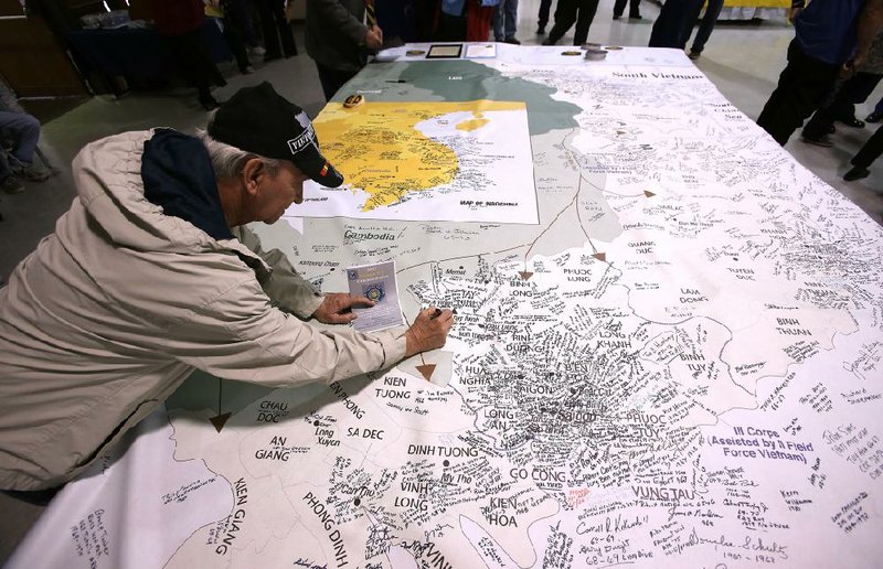 Before Friday’s ceremony in North Little Rock, Army veteran James Collado of Little Rock signs his name on a map of what was once South Vietnam, near the city of Tay Ninh where he was stationed. More photos are available at arkansasonline.com/330vietnamvets/. 