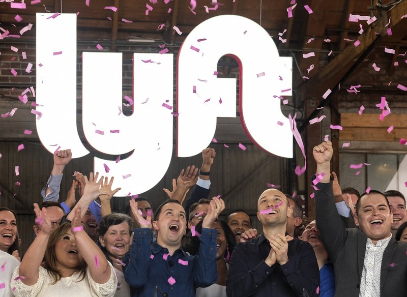 Lyft co-founders John Zimmer, front second from left, and Logan Green, front second from right, cheer as they as they ring a ceremonial opening bell in Los Angeles, Friday, March 29, 2019. On Friday the San Francisco company's stock will begin trading on the Nasdaq exchange under the ticker symbol "LYFT." (AP Photo/Ringo H.W. Chiu)