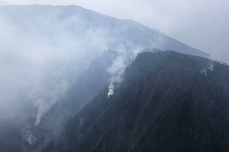 Smoke can be seen from a forest fire in Yalongjiang township in southwestern China’s Sichuan Province on Monday. 
