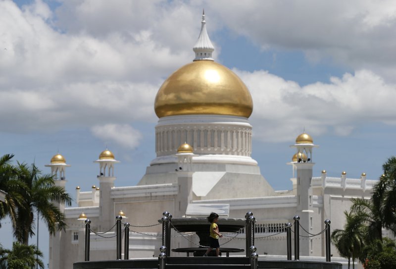 In this April 23, 2013, photo, a child walks near Sultan Omar Ali Saifuddien Mosque, one of the landmarks of Bandar Seri Begawan in Brunei. Brunei announced to implement Islamic criminal laws that punishes gay sex by stoning offenders to death. The legal change in the tiny, oil-rich monarchy, which also includes amputation for theft, is due to come into force Wednesday, April 3, 2019. (AP Photo/Vincent Thian)