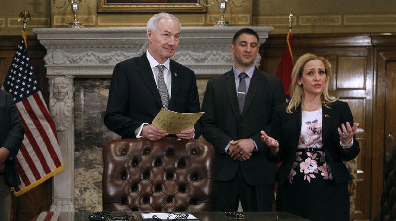 Arkansas Attorney General Leslie Rutledge talks about a new law that increases penalties for phone scammers and robocallers at a bill-signing ceremony Wednesday with Gov. Asa Hutchinson (left) and Rep. Clint Penzo, R-Springdale. More photos are available at www.arkansasonline.com/44genassembly/ 