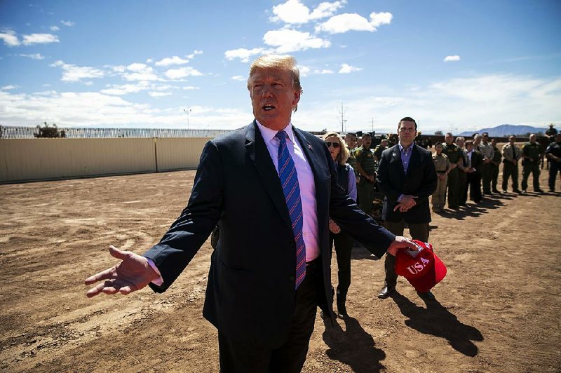 President Donald Trump inspects a newly upgraded section of border fencing Friday in Calexico, Calif. He said “a colossal surge” of illegal crossings is overwhelming the immigration system. 