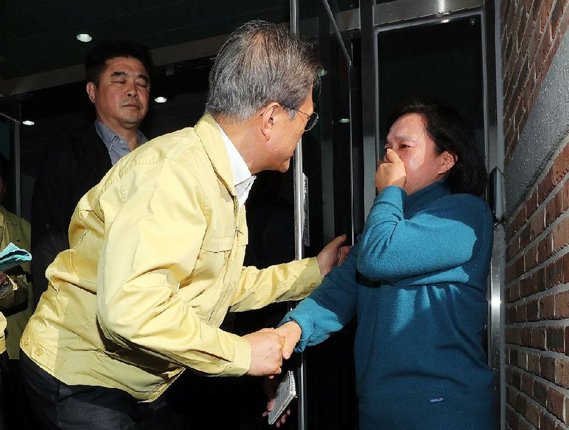 South Korean President Moon Jae-in (left) consoles a resident at a shelter in Goseong, South Korea, on Friday after a fire destroyed 135 homes and forced 4,000 people to evacuate. 