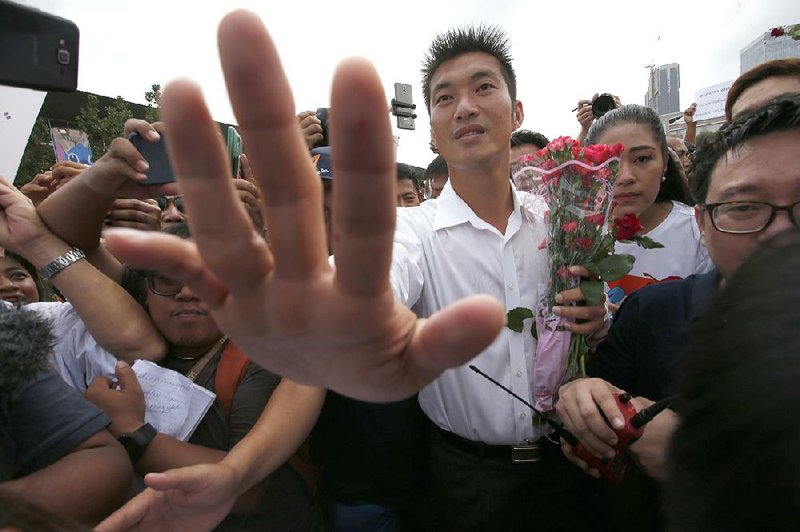 Future Forward Party leader Thanathorn Juangroongruangkit arrives Saturday at a Bangkok police station. Hundreds of supporters greeted him outside the station and chanted, “Keep fighting, Thanathorn!” 