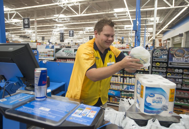 NWA Democrat-Gazette/BEN GOFF &#8226; @NWABENGOFF Jonathan Cousins, Walmart store employee, rings up a customer Aug. 3, 2017, at the Walmart Supercenter on Pleasant Crossing Boulevard in Rogers. Sales tax revenue continues to increase across Northwest Arkansas cities and counties.
