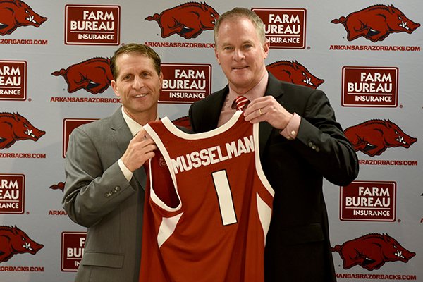 Arkansas basketball coach Eric Musselman (left) and Arkansas athletics director Hunter Yurachek hold up a jersey prior to a news conference Monday, April 8, 2019, at Bud Walton Arena in Fayetteville. 