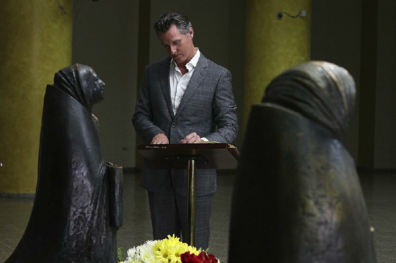 California Gov. Gavin Newsom pays a visit Sunday to the Metropolitan Cathedral in San Salvador, El Salvador, writing a note on a book at the the tomb of St. Oscar Romero. The priest was assassinated in 1980 because of his advocacy for human rights and the poor. 