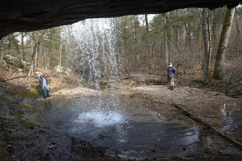 NWA Democrat-Gazette/FLIP PUTTHOFF Visitors can walk into a bluff shelter behind this Madison County waterfall for a unique view. Linda and Dennis Heter take in the watery view.