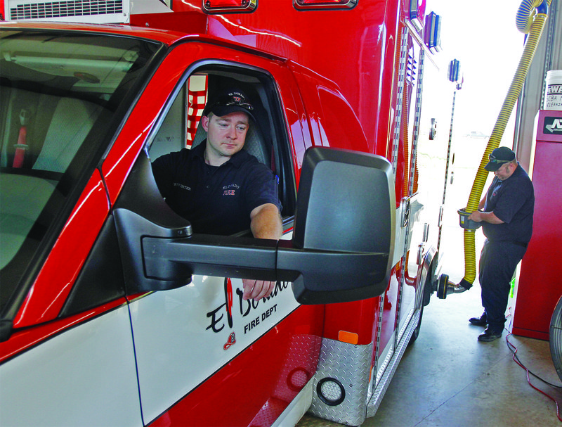 EFD: El Dorado Firefighter Wesley McCulough, left, watches in the driver’s seat of an ambulance as Lt. Justin Green connects the exhaust pipe of the vehicle to the hose of the station’s new diesel exhaust extraction system. The system redirects fumes from the vehicles diesel engine to a safe area outside the fire station. Terrance Armstard/News-Times