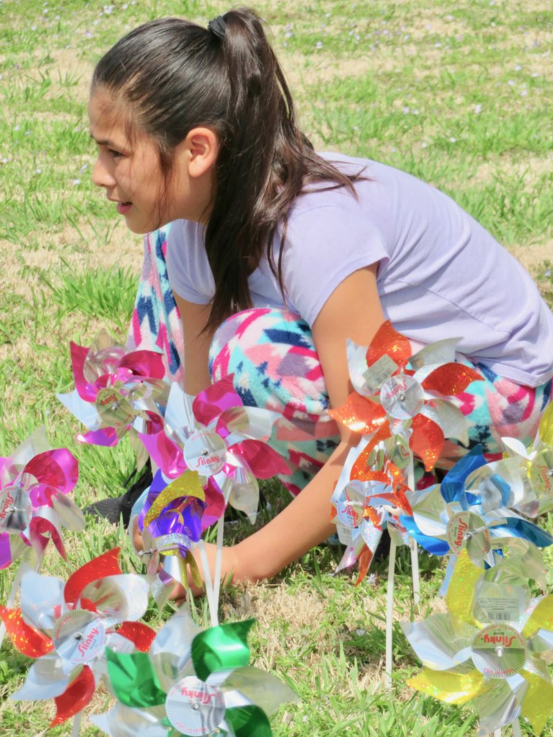 Westside Eagle Observer/RANDY MOLL Ximena Morales, a fifth-grade student at Gentry Intermediate School, was one of a group of fifth-graders who placed pinwheels in the yard at the Gentry Police Station to make people aware of the large numbers of child abuse cases in Benton County each year. There were 353 confirmed cases in Benton County alone last year.