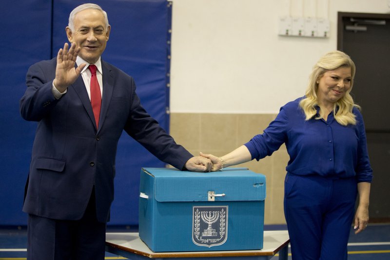 Israeli Prime Minister Benjamin Netanyahu, left, waves with his wife Sara after voting during Israel's parliamentary elections in Jerusalem, Tuesday, April 9, 2019 (AP Photo/Ariel Schalit, Pool)