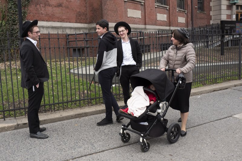 A woman, right, who identified herself as Ester, passes a group of boys, Tuesday, April 9, 2019, in the Williamsburg section of Brooklyn, New York. Ester says that she does not believe that the measles vaccination is safe. The city health department ordered all ultra-Orthodox Jewish schools in a neighborhood of Brooklyn on Monday to exclude unvaccinated students from classes during the current measles outbreak. In issuing the order, the health department said that any yeshiva in Williamsburg that does not comply will face fines and possible closure.(AP Photo/Mark Lennihan)