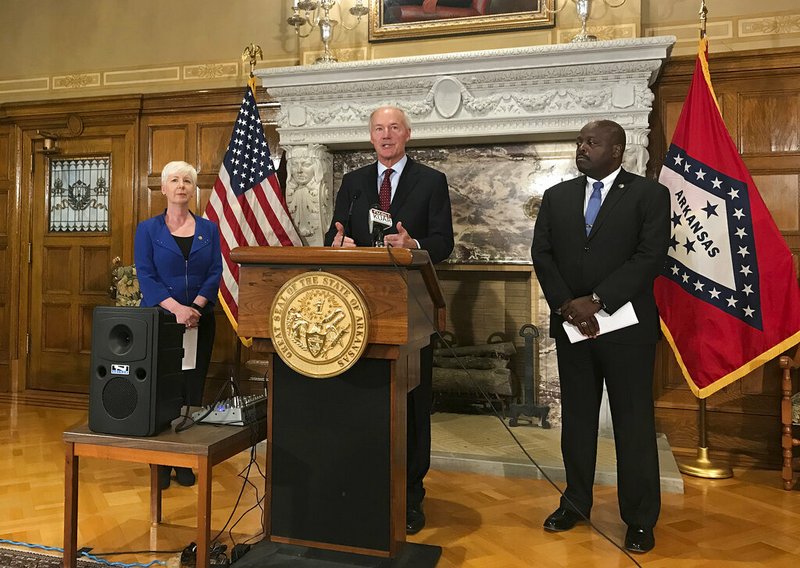 In this Sept. 12, 2018, file photo, Arkansas Gov. Asa Hutchinson, center, talks at a news conference at the State Capitol in Little Rock, Ark., about the state's work requirement for its expanded Medicaid program. Federal judge James Boasberg is blocking Medicaid work requirements in Arkansas and Kentucky, dealing a blow to the Trump administration's efforts to push the poor toward self-sufficiency. 