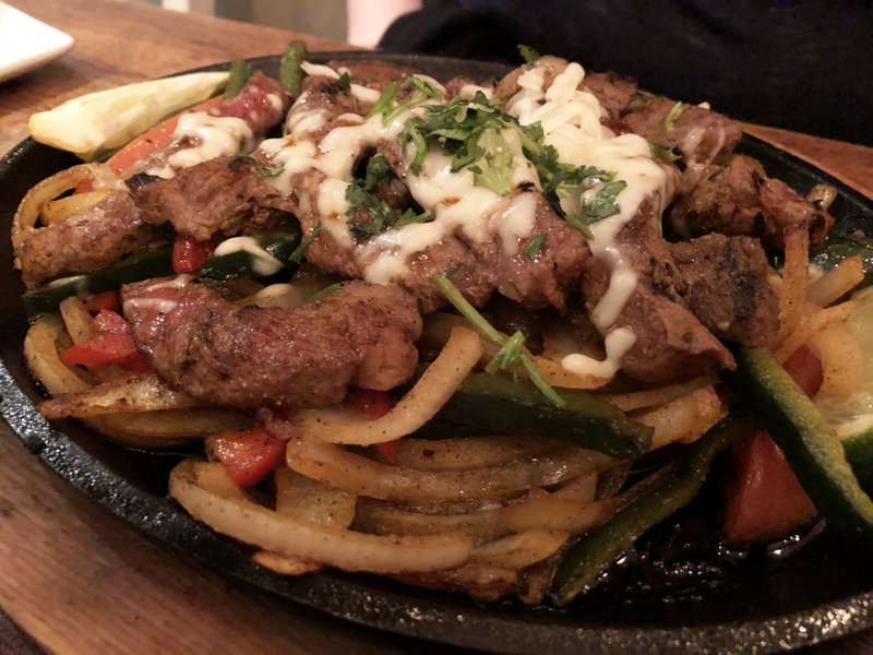 Grilled Ribeye Fajitas at Local Lime come on a bed of onions and peppers, garnished with cilantro and cheese and with sides of Just-Made Guacamole, pico de gallo, tomato, radish, sour cream and fresh flour tortillas. Arkansas Democrat-Gazette/Celia Storey
