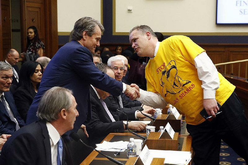 Brian Moynihan (left), chief executive of Bank of America, greets a spectator Friday during a break at a House Financial Services Committee hearing. Moynihan’s testimony was interrupted by the leader of a housing-advocacy group.