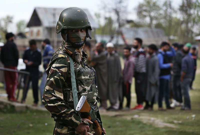 A soldier stands guard Thursday outside Srinagar as Kashmiris line up to cast their votes. 