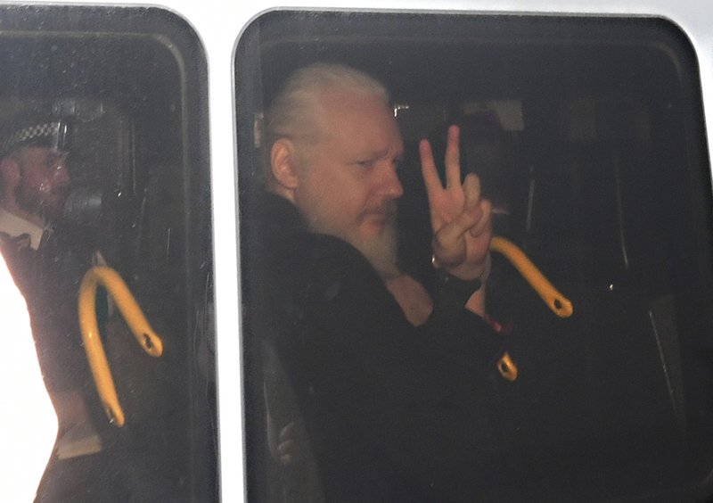 Julian Assange gestures as he arrives at Westminster Magistrates' Court in London, after the WikiLeaks founder was arrested by officers from the Metropolitan Police and taken into custody Thursday April 11, 2019. Police in London arrested WikiLeaks founder Assange at the Ecuadorean embassy Thursday, April 11, 2019 for failing to surrender to the court in 2012, shortly after the South American nation revoked his asylum .(Victoria Jones/PA via AP)